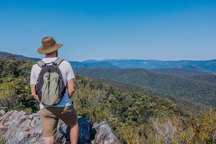 Man overlooking sunlit hinterland ranges on a crisp clear day—perfect for hiking and scenic views during the Gold Coast in winter.