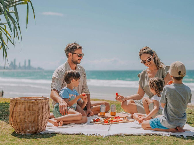 Family enjoying a sunny beachside picnic with views of the ocean and skyline — a perfect way to celebrate Mother's Day Gold Coast style with connection, nature, and fresh air.