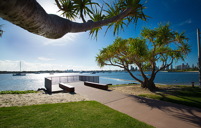 Scenic waterfront walkway at Broadwater Parklands, with shaded seating, views of the marina, and open green spaces—one of the top things to do in Southport for families and nature lovers.