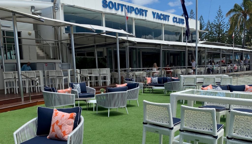 Outdoor seating at the Southport Yacht Club, one of the best restaurants in Gold Coast, featuring stylish lounge chairs, shaded tables, and waterfront views on a sunny day.